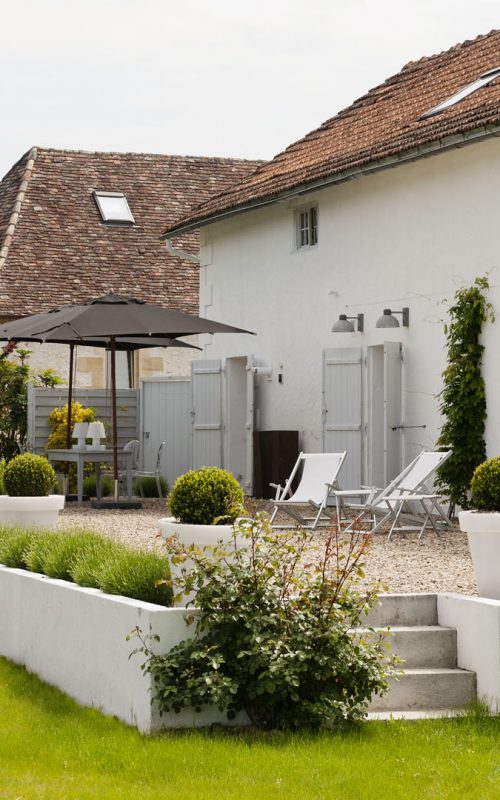 Exterior facade of converted barn with shutters and gravel terrace