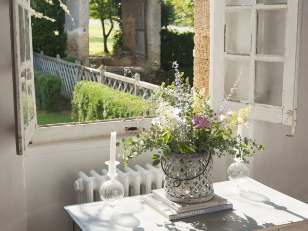 Small wooden writing desk by open windows with view to garden